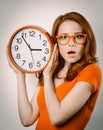 Surprised redhead girl with huge alarm clock Royalty Free Stock Photo