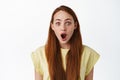 Surprised redhead young woman, gasp fascinated, looking in awe with dropped jaw, impressed by something cool, standing