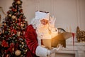 Surprised Santa Claus with a magical glowing gift near beautiful christmas tree. New year and Merry Christmas , happy holidays