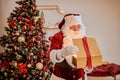 Surprised Santa Claus with a magical glowing gift near beautiful christmas tree. New year and Merry Christmas , happy holidays