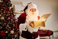 Surprised Santa Claus with a magical glowing gift near beautiful christmas tree. New year and Merry Christmas , happy holidays