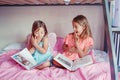 Surprised scared Caucasian sisters girls reading books in bedroom. Home schooling children siblings learned saw unexpected in a