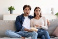 Surprised scared young european couple with open mouths eating popcorn and watching movie