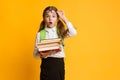 Surprised Schoolgirl Looking At Camera Holding Stack Of Books, Studio Royalty Free Stock Photo