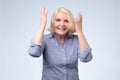 Surprised senior blonde woman with hands up amazed or shocked by unexpected news