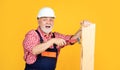 surprised senior man woodworker in helmet on yellow background