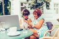 Two happy senior women watching media content in a smart phone in a cafe Royalty Free Stock Photo