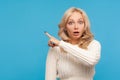 Surprised shocked blond woman in knitted sweater pointing finger away at empty blank for your advertisement, wondered with Royalty Free Stock Photo
