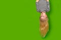 Surprised shocked little blonde girl hanging happy upside down over isolated green studio background. Emotion Royalty Free Stock Photo