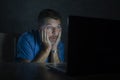 Surprised and shocked man at night working with laptop computer in the dark in disbelief and surprise face expression watching Royalty Free Stock Photo