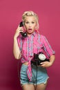 Surprised shocked pin-up woman answers a phone call on pink Royalty Free Stock Photo