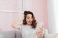 Surprised shocked woman looking at phone screen sitting on a sofa in apartment at home Royalty Free Stock Photo