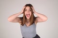 Surprised shocked young girl isolated over gray studio background. Close up shot of emotive shocked young woman opens