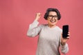 Surprised smiling happy senior mature aged senior woman in casual showing blank smartphone screen while looking at the camera Royalty Free Stock Photo