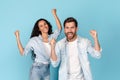 Surprised smiling millennial caucasian male with beard and arab lady in casual raising hands up