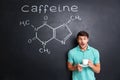 Surprised student drinking coffee over drawn structure of caffeine molecule Royalty Free Stock Photo