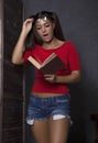 Surprised student girl reading a book. young woman in red top and denim shorts with glasses Royalty Free Stock Photo