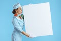 surprised stylish female stewardess on blue showing blank board