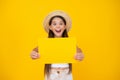 surprised teen girl hold empty advertisement paper with copy space on yellow background