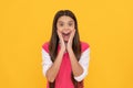 surprised teen school girl smiling with long hair on yellow background, surprise Royalty Free Stock Photo