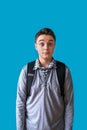 Surprised teenage boy with a backpack, stunned by shocking news, on a blue background Royalty Free Stock Photo