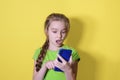Surprised teenage girl looking at her mobile phone screen. Child girl uses a smartphone