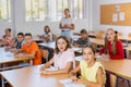 Surprised tween schoolchildren sitting at school desks at lesson Royalty Free Stock Photo