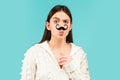 Surprised winking model Girl holding funny mustache on stick and showing empty copy space on open hand palm for text Royalty Free Stock Photo