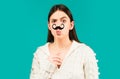 Surprised winking model Girl holding funny mustache on stick and showing empty copy space on open hand palm for text Royalty Free Stock Photo