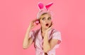 Surprised woman in bunny ears with pink eggs. Happy Easter. Hunting eggs. Amazed girl with colored egg. Spring holiday.