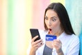 Surprised woman buying online with credit card outside Royalty Free Stock Photo
