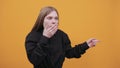 Surprised woman covered mouth with hand, pointing finger aside