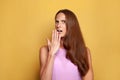 Surprised woman covering her mouth her hand over yellow background and looking at camera Royalty Free Stock Photo