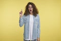 Surprised woman with curly hair has stunned expression, pointing with index finger up, wears eyeglasses and dressed Royalty Free Stock Photo