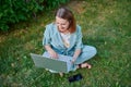 surprised woman with laptop sitting on green grass Royalty Free Stock Photo