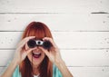 Surprised woman looking through binoculars against white background