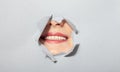 Surprised woman looking playfully in torn paper hole, has excited cheerful expression, looks through breakthrough of Royalty Free Stock Photo