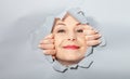 Surprised woman looking playfully in torn paper hole, has excited cheerful expression, looks through breakthrough of gray Royalty Free Stock Photo