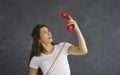 Surprised woman looks confused at red retro handset from landline phone she holds in her hand. Royalty Free Stock Photo