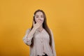 Surprised woman in pastel shirt covered mouth with hand, looking at camera