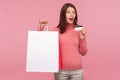 Surprised woman in pink sweater showing credit card and many paper bags looking at camera, excited satisfied with shopping and Royalty Free Stock Photo