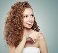 Surprised woman pointing. Beautiful female model girl with long curly hair pointing to the side. Positive emotion. Royalty Free Stock Photo