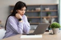 Surprised woman sitting at desk, using laptop