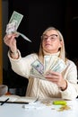 surprised female employee sitting at work and looking at dollar banknotes financial welfare concept