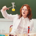 Surprised woman teacher with flask in hand at chemistry lesson at school. Analyzes, tests and research in the school lab