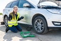 Surprised woman with tools and broken car on roadside