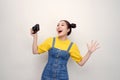 Surprised woman, with top knot hairdo, wearing on denim jumpsuit, holding retro camera, on the white background Royalty Free Stock Photo