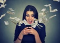 Surprised woman using smartphone dollar bills flying away from screen Royalty Free Stock Photo