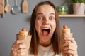 Surprised wondered woman keeps mouth widely opened holds appetizing hot dogs, eating fast food, having cheat meal and unhealthy Royalty Free Stock Photo