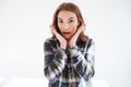 Surprised wondered young woman in plaid shirt with opened mouth